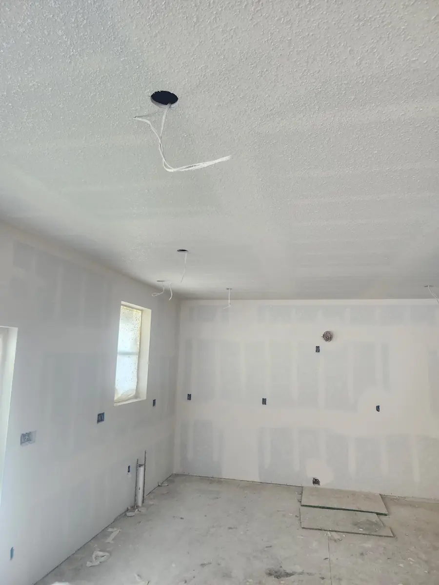Taped and finished drywall room with a textured ceiling before paint