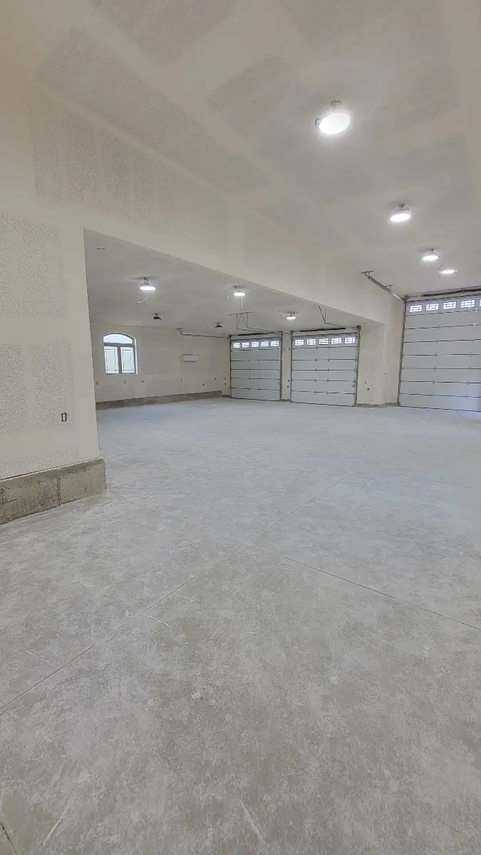 Oversized garage with fully drywalled and textured walls and ceiling