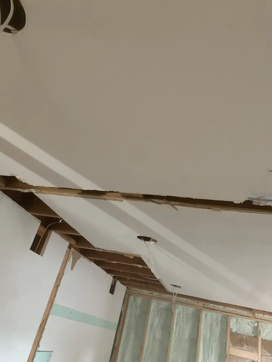 Drywall installed on a remodeled ceiling with exposed rafters and spray-foam insulation